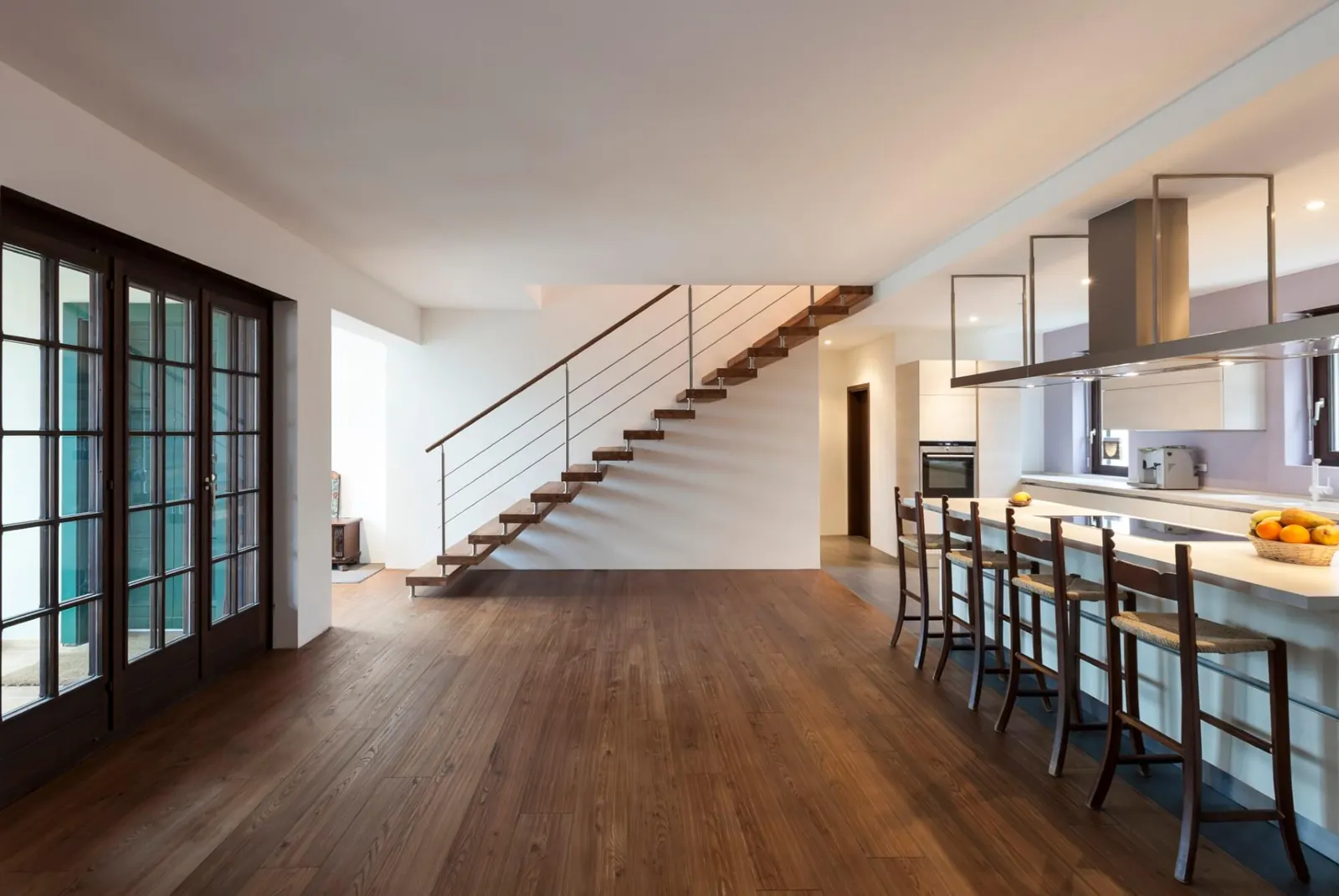 Dark hardwood running through a kitchen to a floating staircase